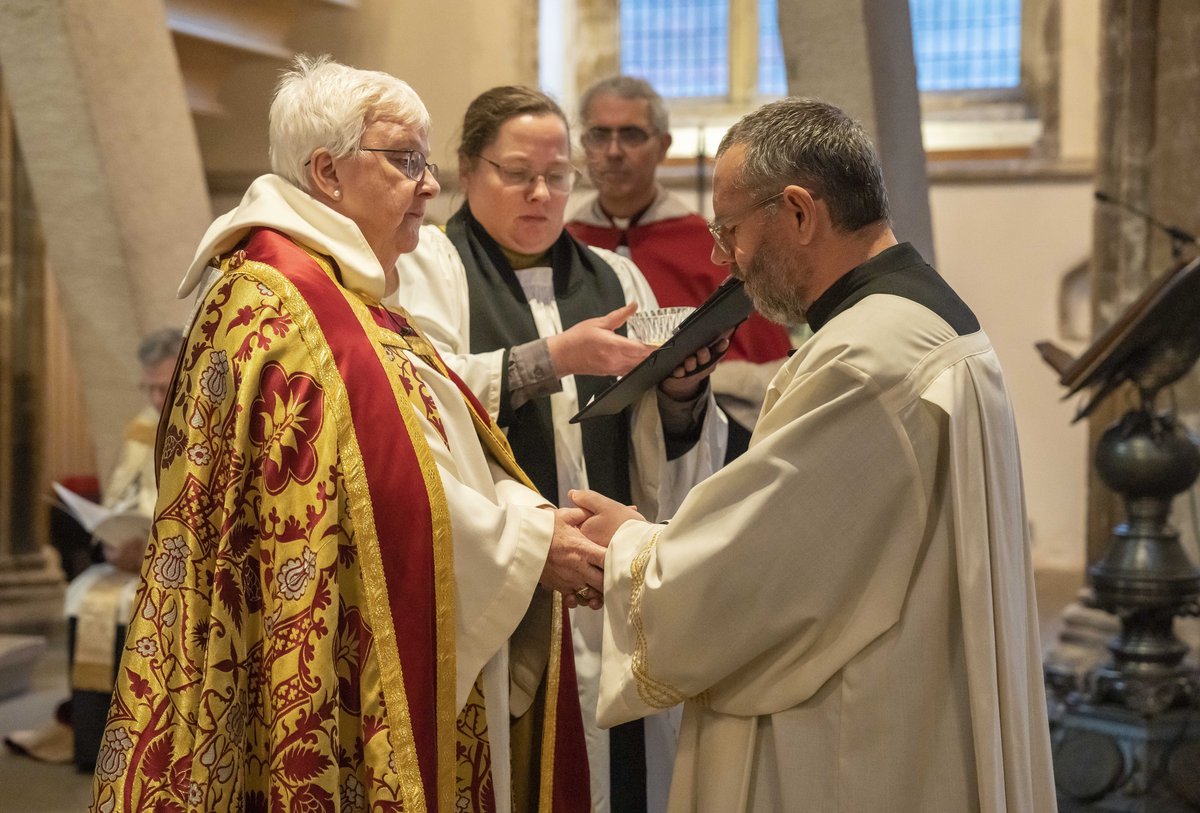 Female bishop places her hand on male priest's head