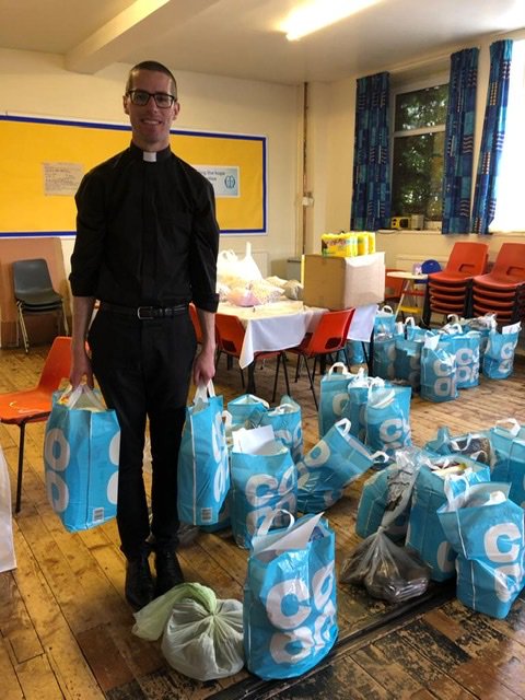 Priest holding a load of shopping bags to give away