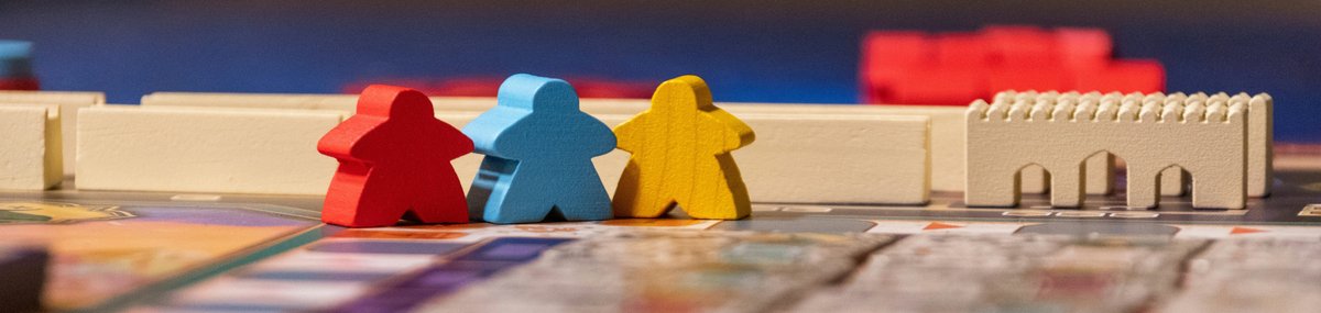 A red, blue and yellow Meeple, wooden figures from a board game, on a game matt