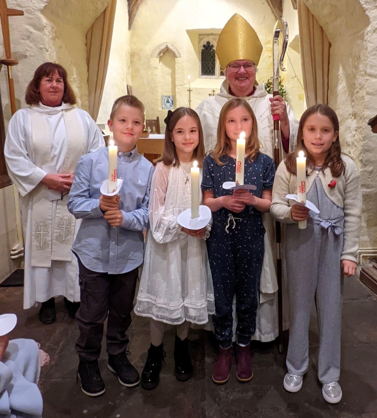 a group of four children holding candles with Bishop June