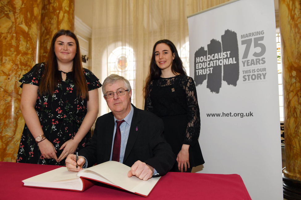 First Minister, Mark Drakeford signing HET’s book of Commitment with Ella Rowlands and Lydia