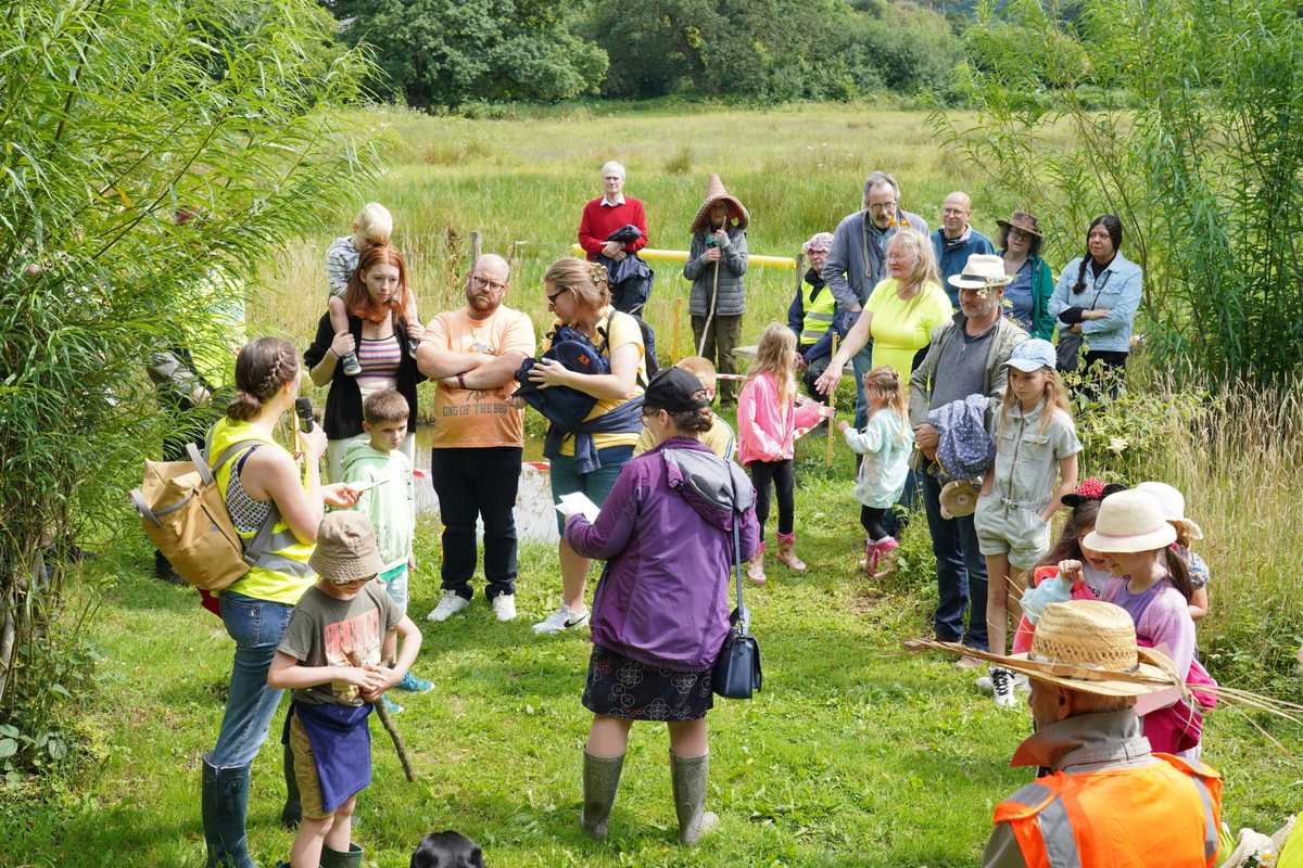 wide shot in field with Bishop Mary and families in wellies