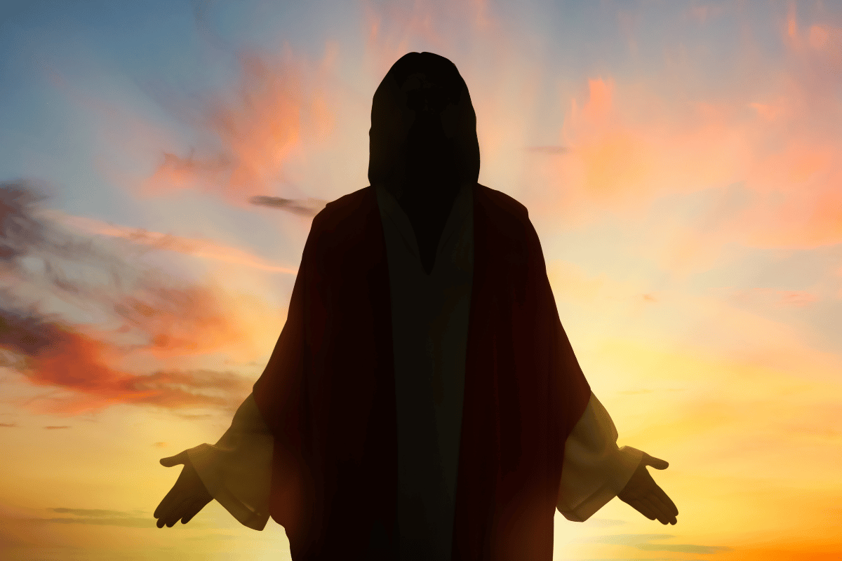 Jesus silhouette standing in orange sunset light