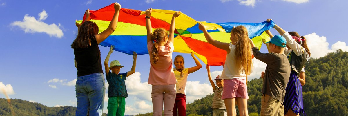 Children playing with a rainbow coloured parachute
