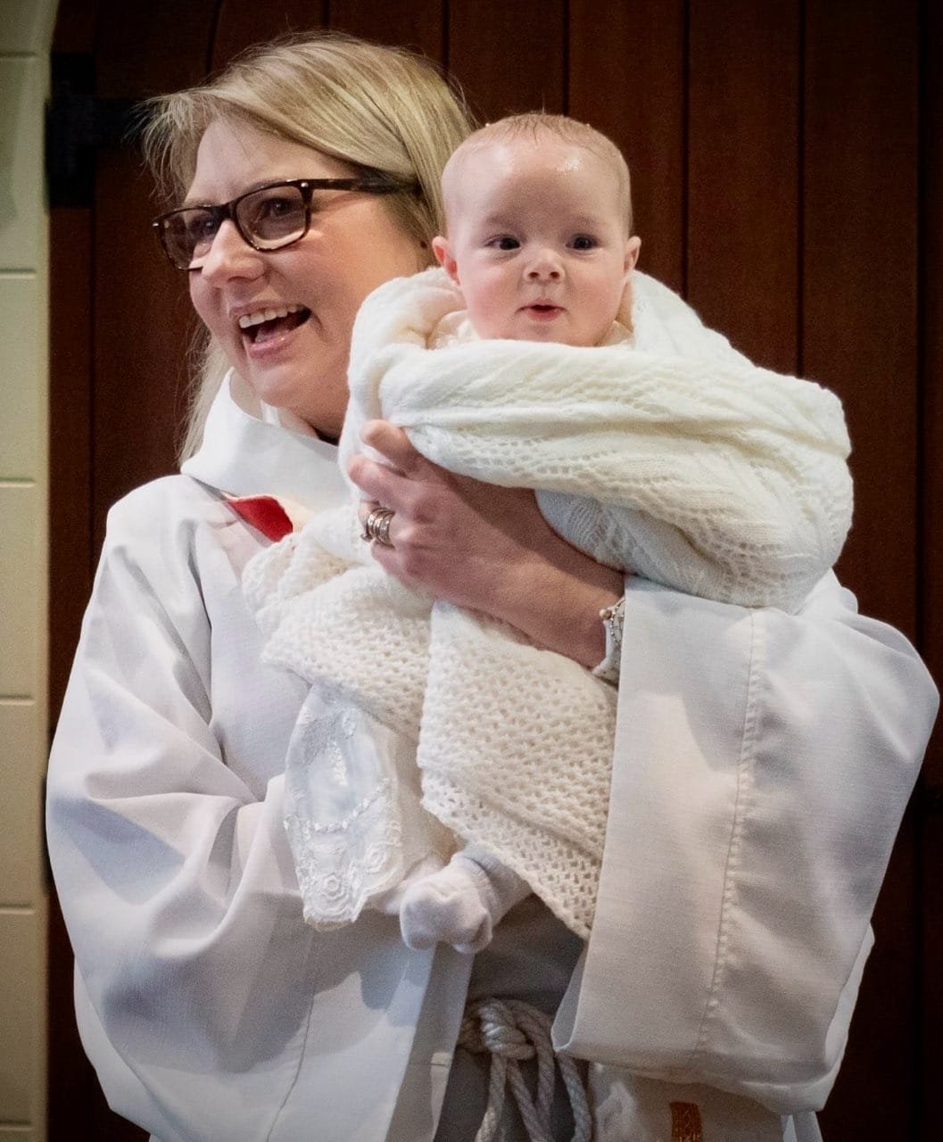 New Bishop's Chaplain Emma Ackland holding an infant during baptism