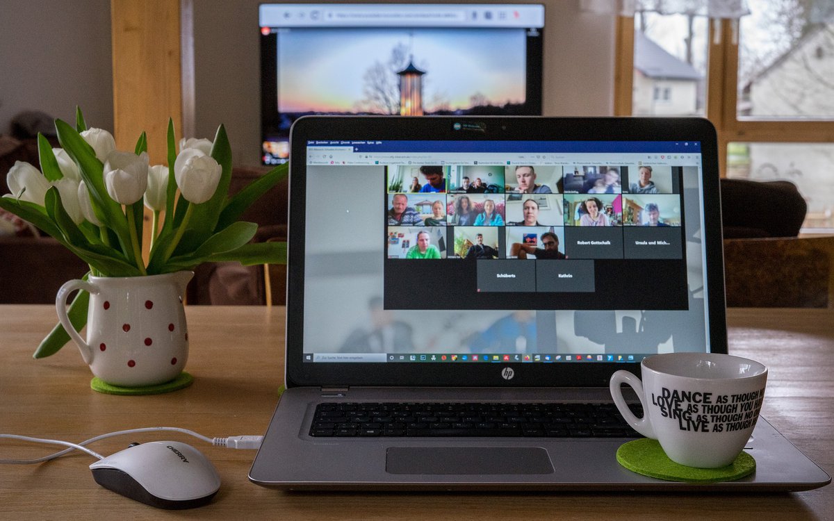 A laptop with a Zoom video call open and a cup of coffee