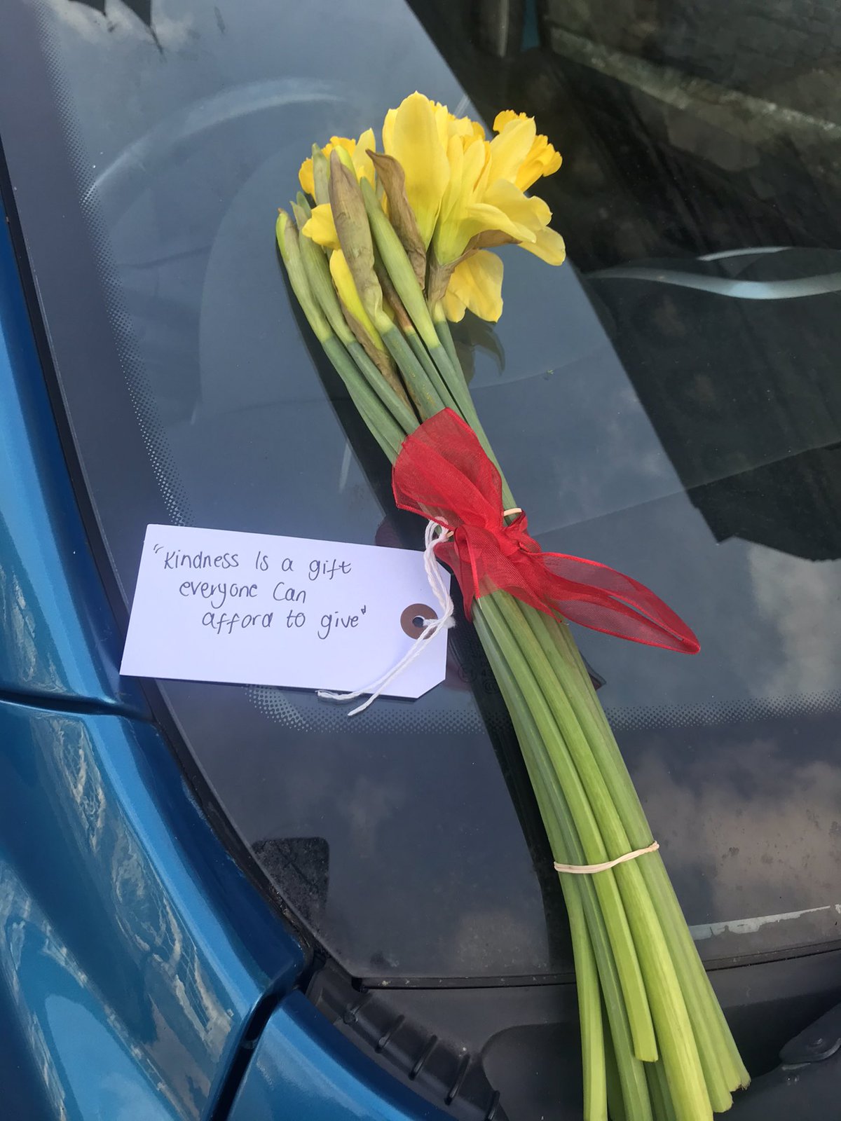 daffodils left on car with a note that reads kindness is a gift everyone can afford to give