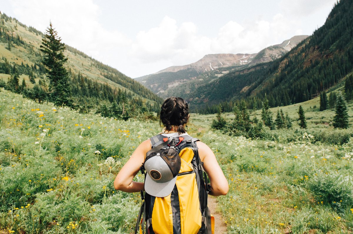 A journeying girl with a backpack looking out at a beautiful valley