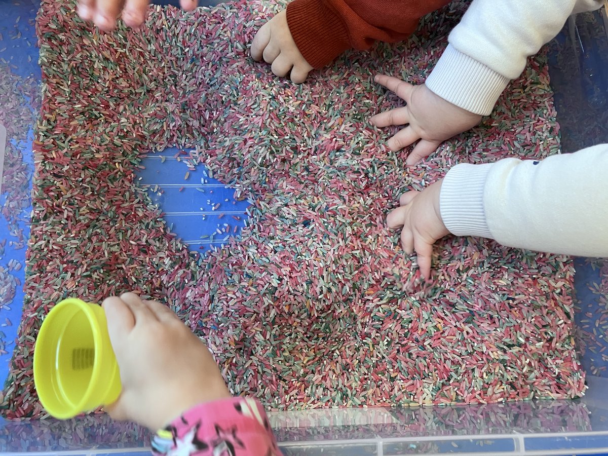 Children's hands playing with coloured rice
