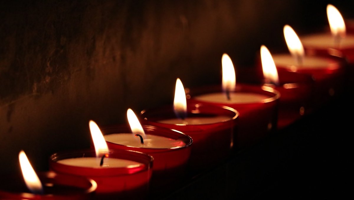 Some candles flicker against a black background